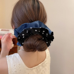 Detail of a large double-layer polka dot and denim hair scrunchie on a bun hairstyle