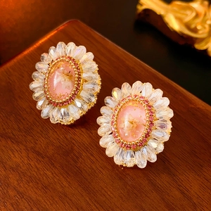 Close-up of luxury flower earrings with pink crystal stones and golden petal details