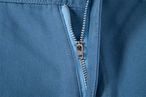Close-up of durable metal zipper on blue cotton canvas shorts with TXC engraved puller