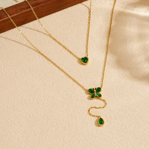 Gold double-layered necklace with green heart and flower pendants and tassel drop accents