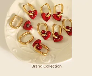 Macro view of gold oval earrings with glossy red heart charms on a white relief plate