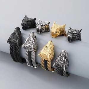 Close-up of wolf head bracelets with braided steel cables in various metal finishes