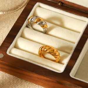 Close-up of gold and two-tone croissant dome rings on a velvet wooden jewelry box