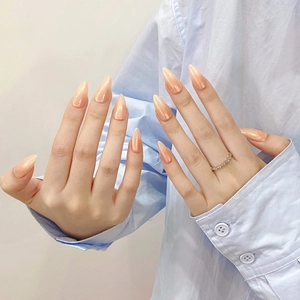 Handmade shimmering peach nude press-on nails in stiletto shape on model hands