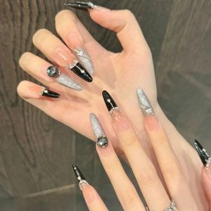 Detail von langen Stiletto-Klebenägeln mit schwarzem Cat-Eye-Effekt und Silbersteinen