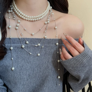 Detail shot of elegant multi-layer pearl fringe necklace on a grey knit sweater
