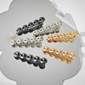 Macro view of metallic round linked hairpins in gold, silver, and black on a mirror base