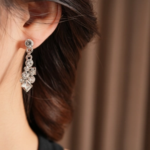Close-up of elegant silver drop earrings with clear diamonds worn by a model