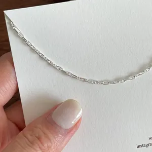 Macro shot of minimalist S925 sterling silver anchor link chain on white background card