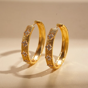Detailed view of 18k gold flower earrings with zircons and brushed metal texture