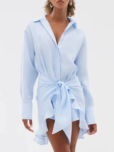 Close-up of light blue linen shirt dress with waist tie and ruffled asymmetrical hemline