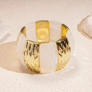 Close-up of wide stretch bracelet featuring gold wavy metal and acrylic marble textures
