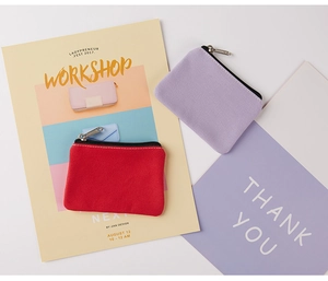 Flat lay of small canvas coin purses in red and lilac with metallic zipper details