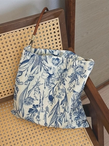 Retro blue floral print canvas tote bag with brown handles on a woven chair