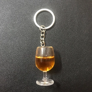 Close-up of a resin wine glass keychain with amber liquid on black leather texture