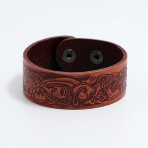 Detailed macro view of vintage brown leather bracelet with embossed Celtic dragon pattern