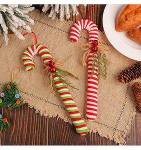 Detail of red and white striped Christmas candy cane ornaments with bells and pine needles