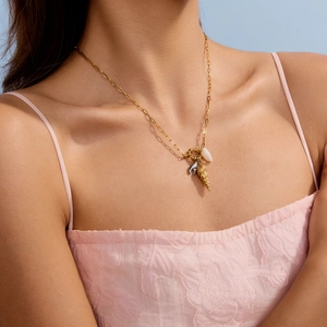 Close-up of sailor clasp necklace with gold conch, silver dolphin and shell charms