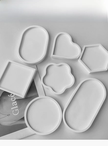 Vista dettagliata di sette stampi in silicone bianco per sottobicchieri e vassoi in resina