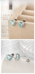 Macro detail of silver heart stud earrings with light blue zircon and threaded backing