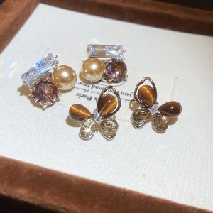Détail de boucles d'oreilles papillon vintage avec zircon et perles sur présentoir