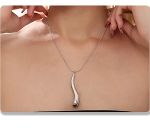 Close-up of a silver teardrop pendant necklace worn by a model to show glossy finish