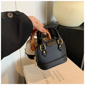 Détail de mini sacs coquilles en noir et beige avec grain litchi et finitions dorées