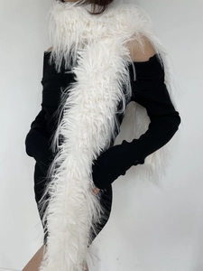 Detail view of a white faux fur long scarf on a model wearing a black knit dress