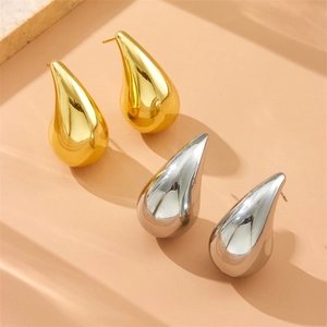 Polished hollow teardrop earrings set in gold and silver finishes on a warm background