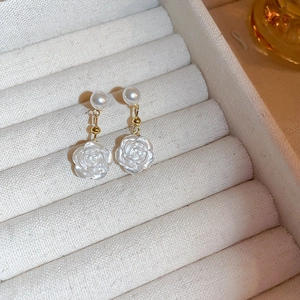 Detail of white flower and pearl earrings showcased in a beige velvet jewelry box
