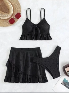 Detailopname van zwarte driedelige bikiniset met oogjesstof en rok met ruches
