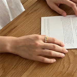Minimalist S925 sterling silver olive bead rings in gold and silver on a wooden table