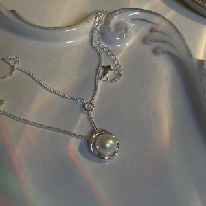 Detailed macro of S925 silver necklace with round pearl and butterfly charm extension