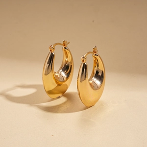 Macro shot of gold horseshoe oval earrings with smooth mirror-polished finish