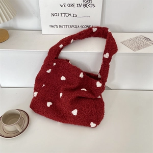 Dettaglio borsa tote in pile rosso con motivi a cuore bianco in un ambiente lifestyle