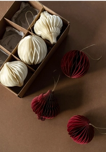 Detail view of red and cream honeycomb paper Christmas ornaments in a gift box