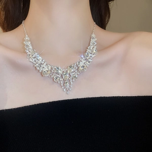 Macro shot of silver crystal teardrop necklace and earrings set on model