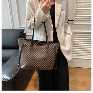 Detail view of a brown checkered tote bag with double straps worn with a white blazer