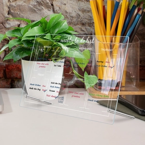 Detailed view of an acrylic weekly to-do list board with a metal stand on a desk