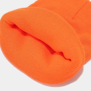 Close-up of orange knitted beanie showing detailed ribbed texture and warm folded cuff