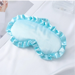 Detail einer hellblauen Schlafmaske aus Satin mit eleganten Rüschen und elastischem Band