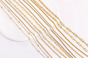 Collection of various 18k gold plated stainless steel chain styles on white podium
