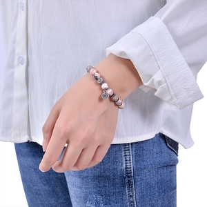 Pink zebra stone bead bracelet with silver compass charm worn on wrist with white shirt