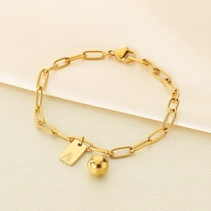 Détail d'un bracelet doré avec plaque carrée lettre A et perle en acier inoxydable