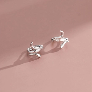 Macro detail of the silver snake-shaped earring with smooth metallic texture and shine