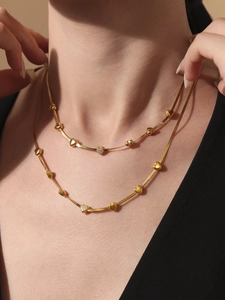 Close-up of dual-layered gold snake bone chains with cubic zirconia heart pendants