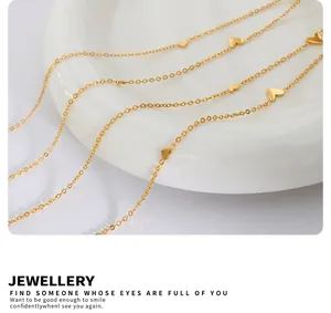 Close-up of a delicate 18K gold-plated heart charm necklace on a white ceramic plate