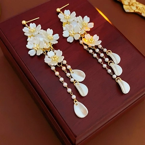 Détail de boucles d'oreilles à fleurs avec glands de perles sur fond de bois