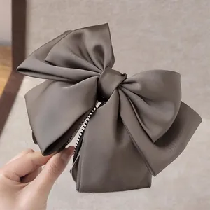Detail of silk satin bow hair clip with strong grip teeth for elegant hairstyles
