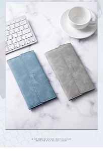 Flat lay of blue and grey frosted leather wallets on white marble desk with a keyboard